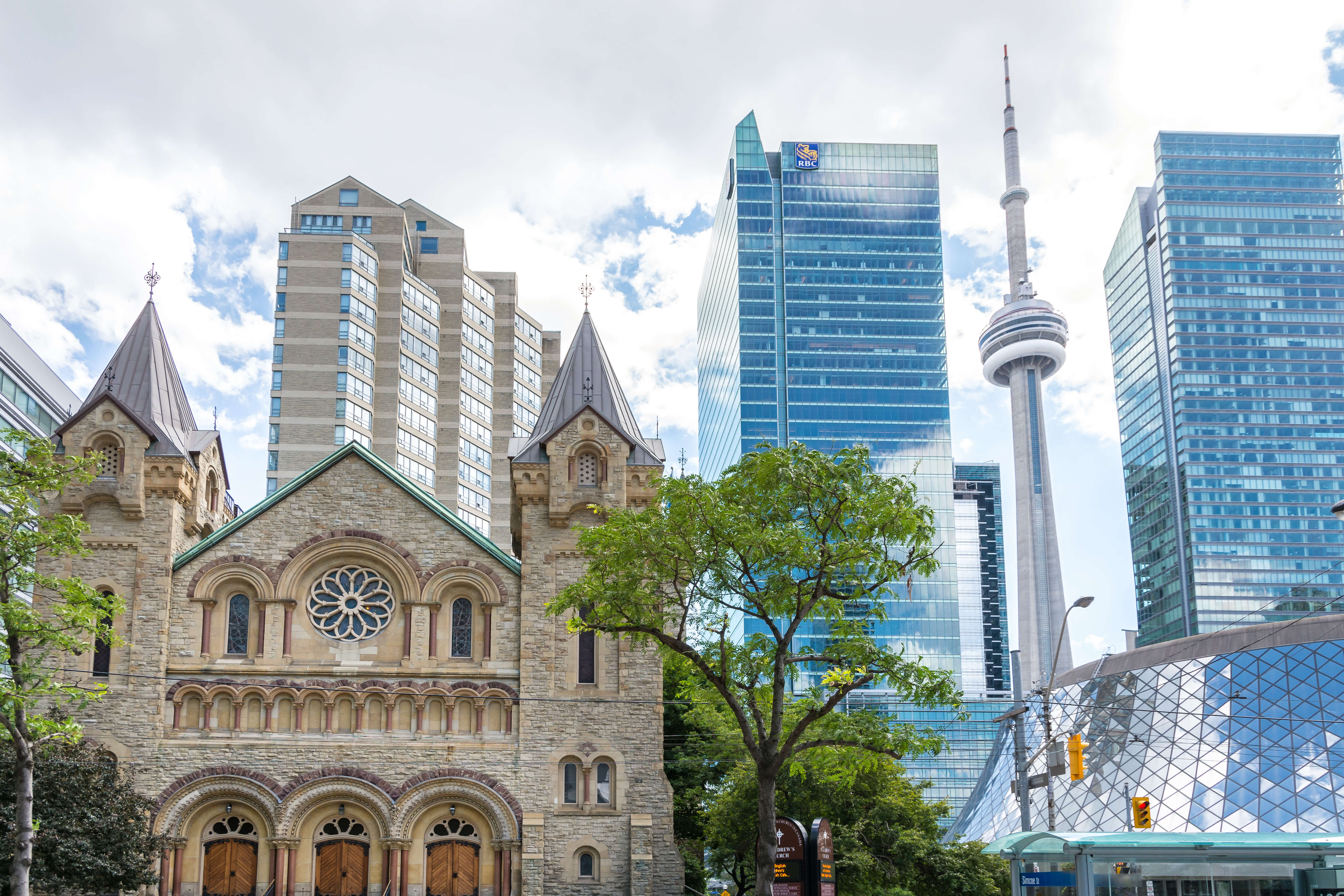 Historic stone building with modern skyscrapers and CN Tower in the background