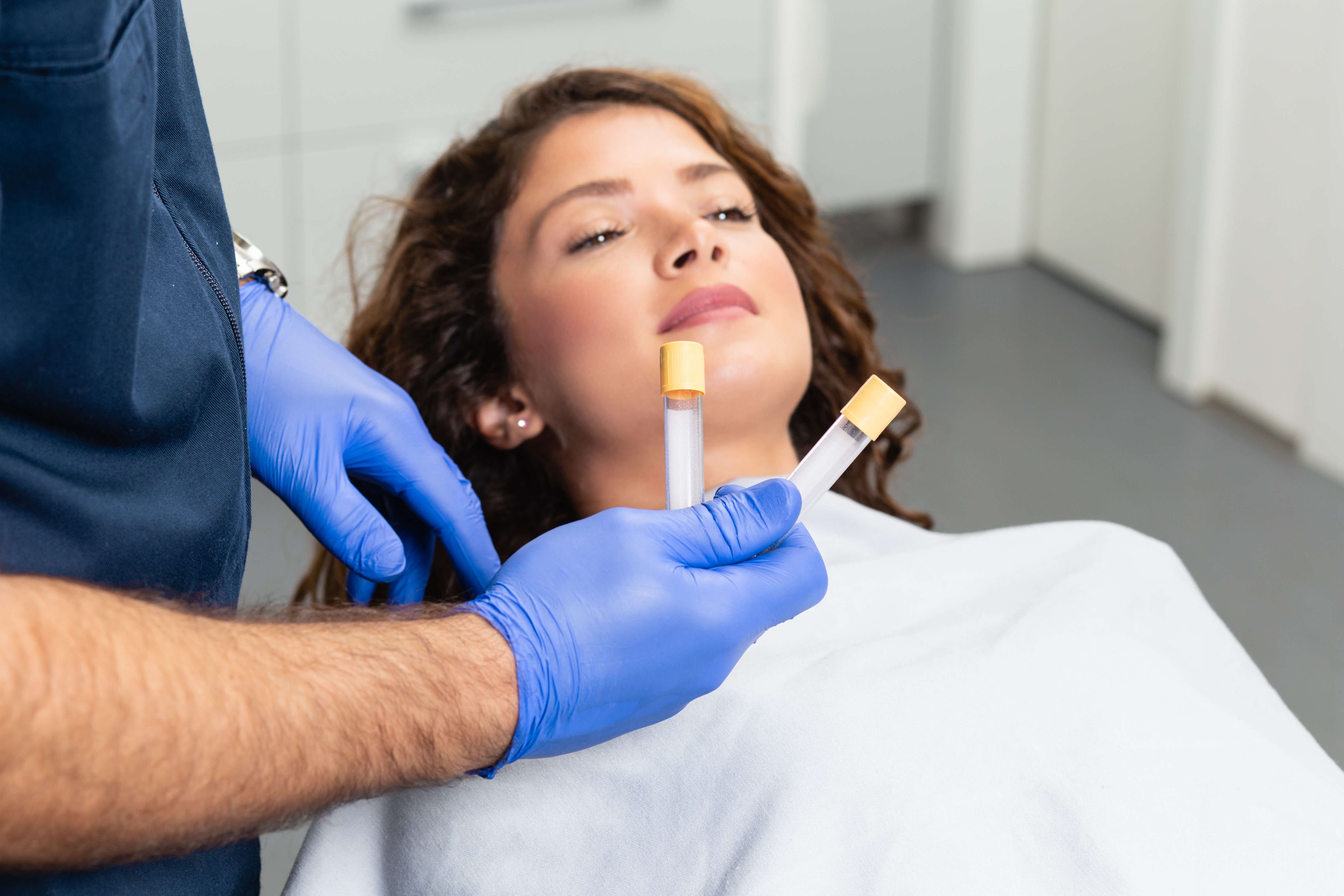 Woman preparing for PRP therapy while holding plasma tubes, in a clinical setting