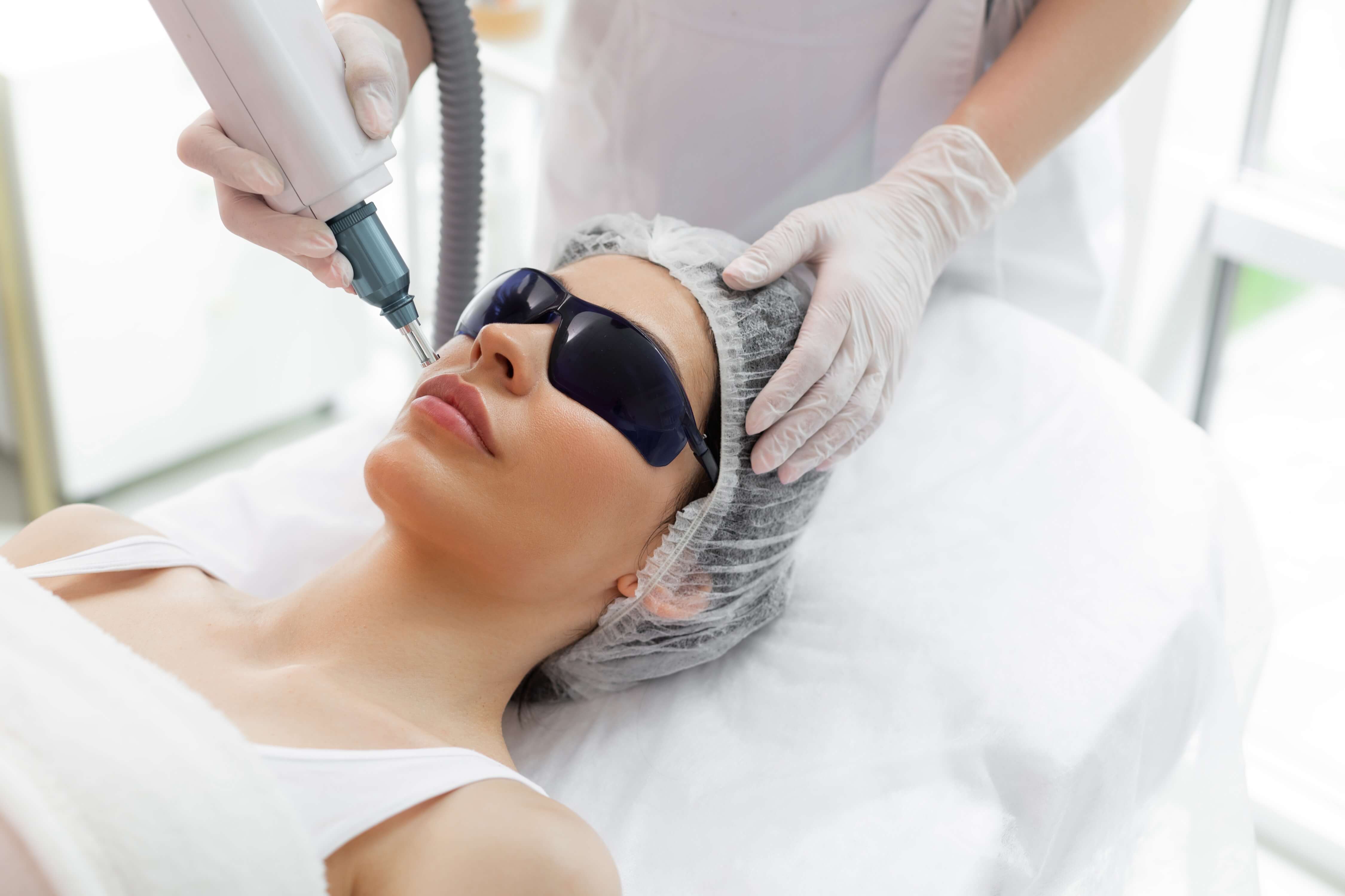 Woman receiving Laser Genesis treatment while wearing protective eyewear, lying down in a clinical setting