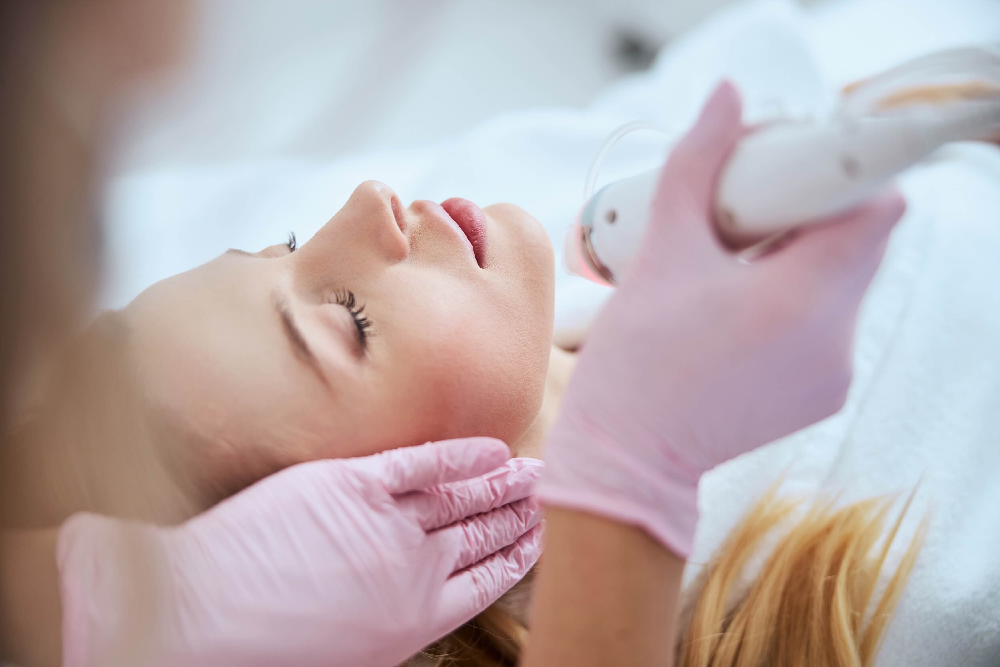 Patient receiving Diamond Glow Facial, with pink-gloved hands performing treatment to enhance skin glow and smoothness.