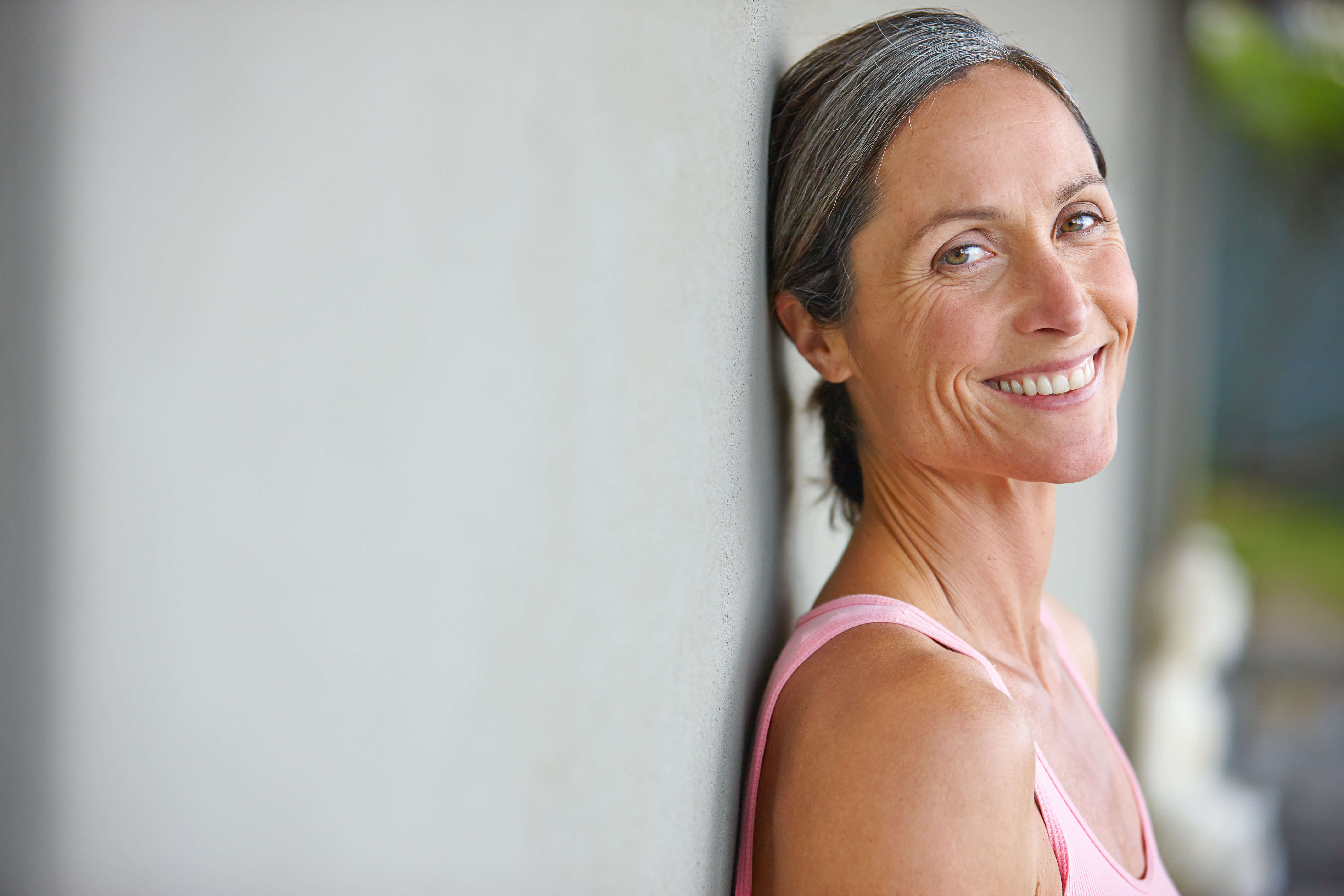 Woman leaning against a wall with a blurred background