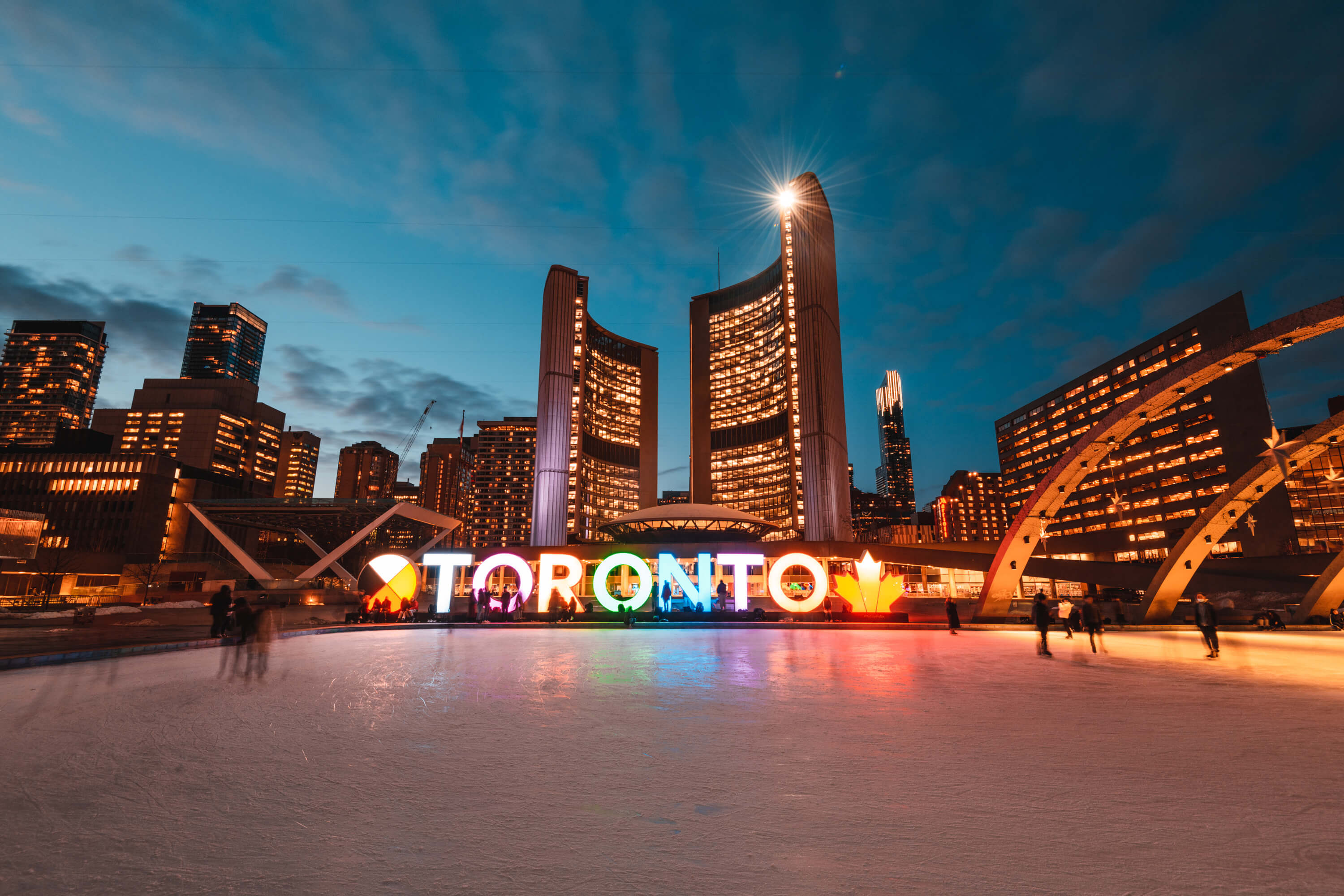 Toronto sign on an ice rink with city skyline at night
