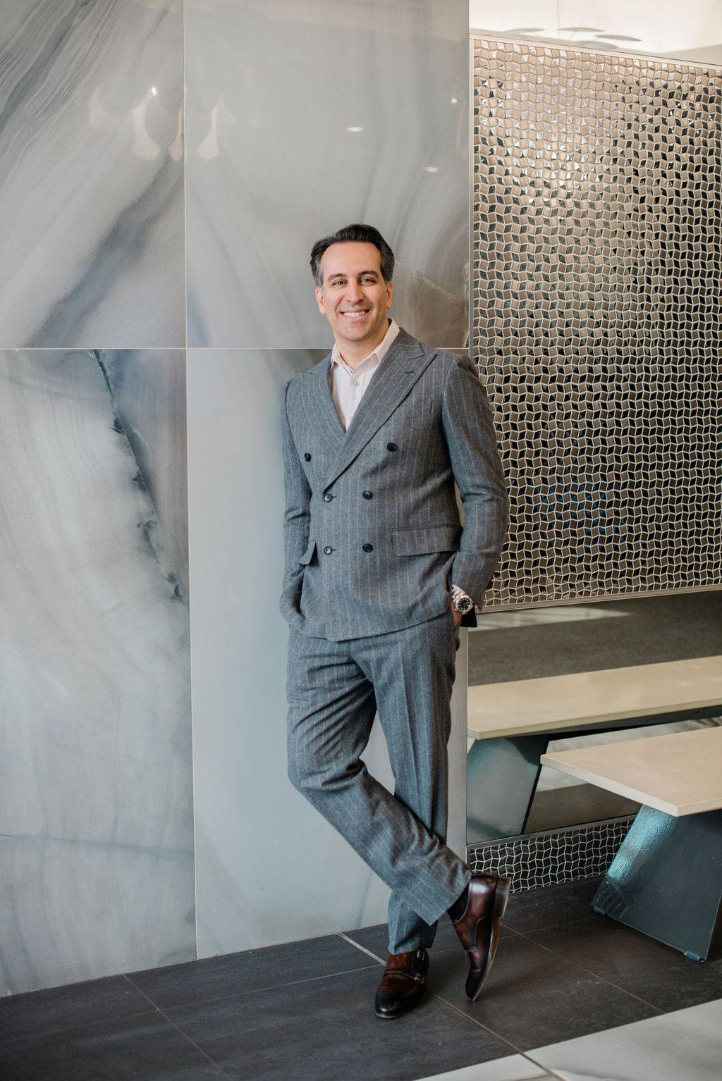 Dr. Babak Maleki standing confidently in a tailored grey suit, representing professionalism and elegance in modern aesthetic medicine