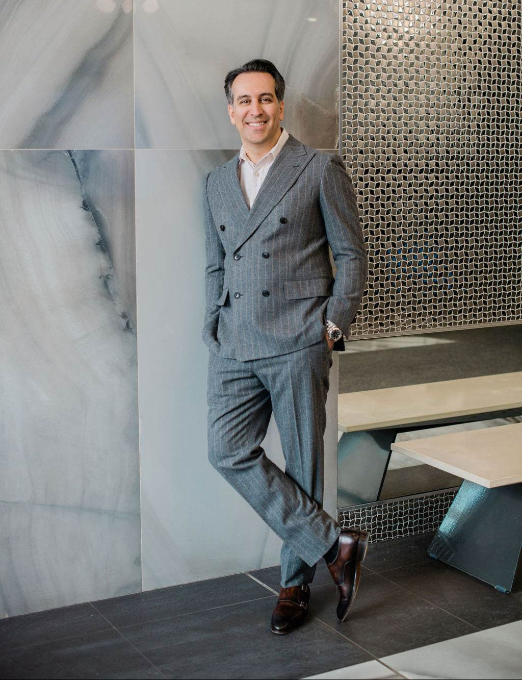 Dr. Babak Maleki standing confidently in a tailored grey suit, representing professionalism and elegance in modern aesthetic medicine