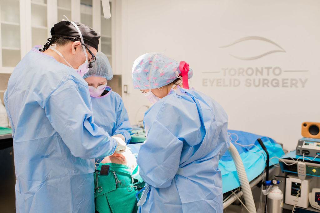 Dr. Babak Maleki performing a facial procedure in a sterile surgical environment with medical team support