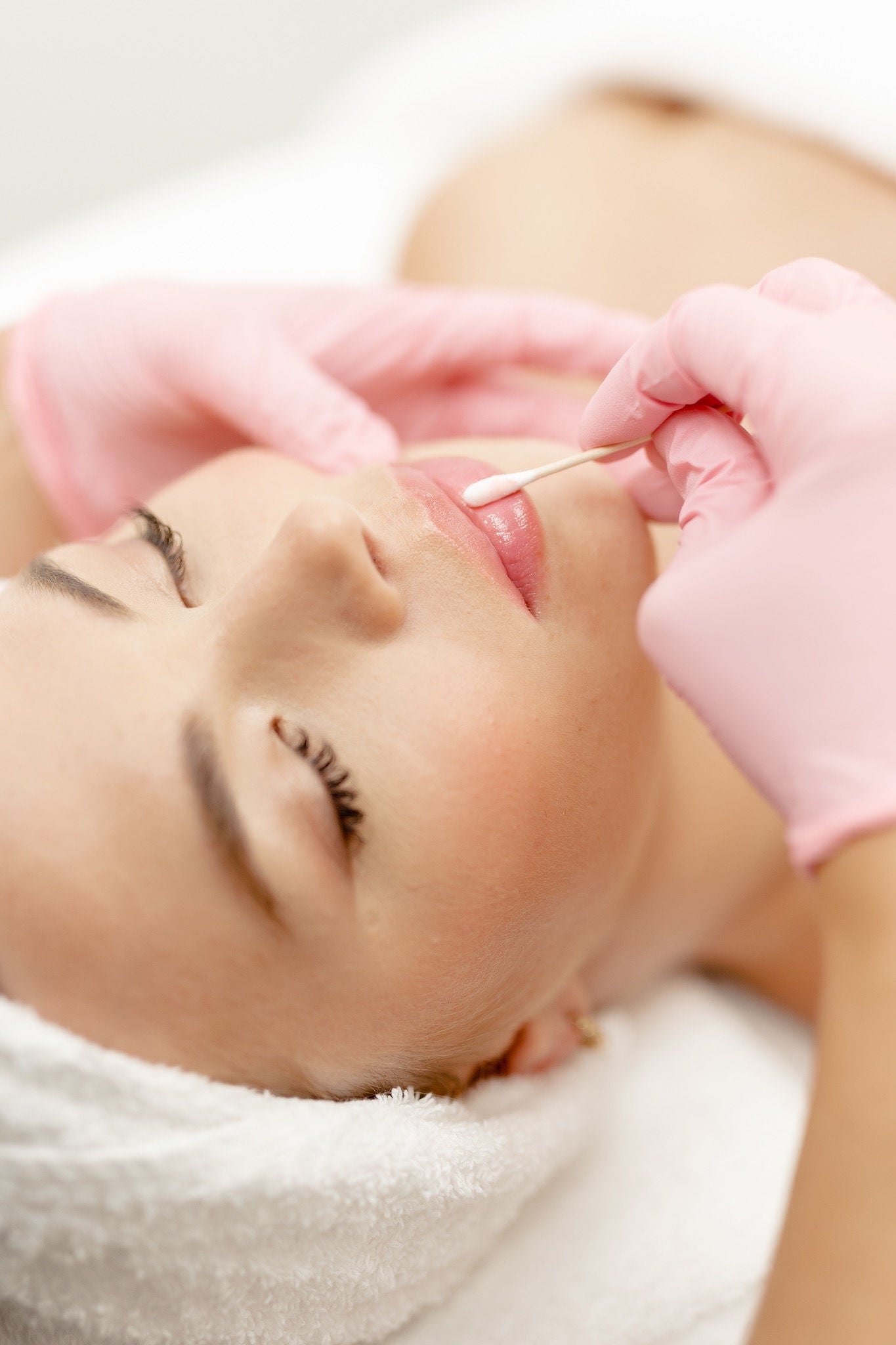 Lip filler treatment with dermal injection performed by aesthetic practitioner in pink gloves