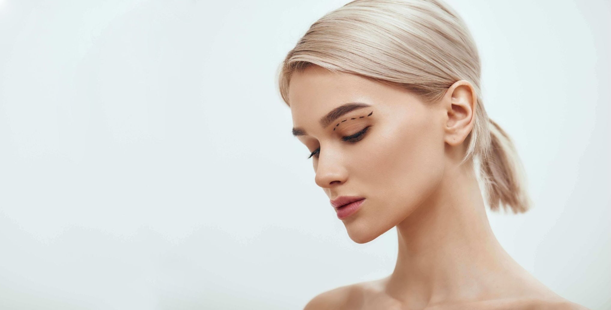 Woman with blonde hair styled in a ponytail against a light background