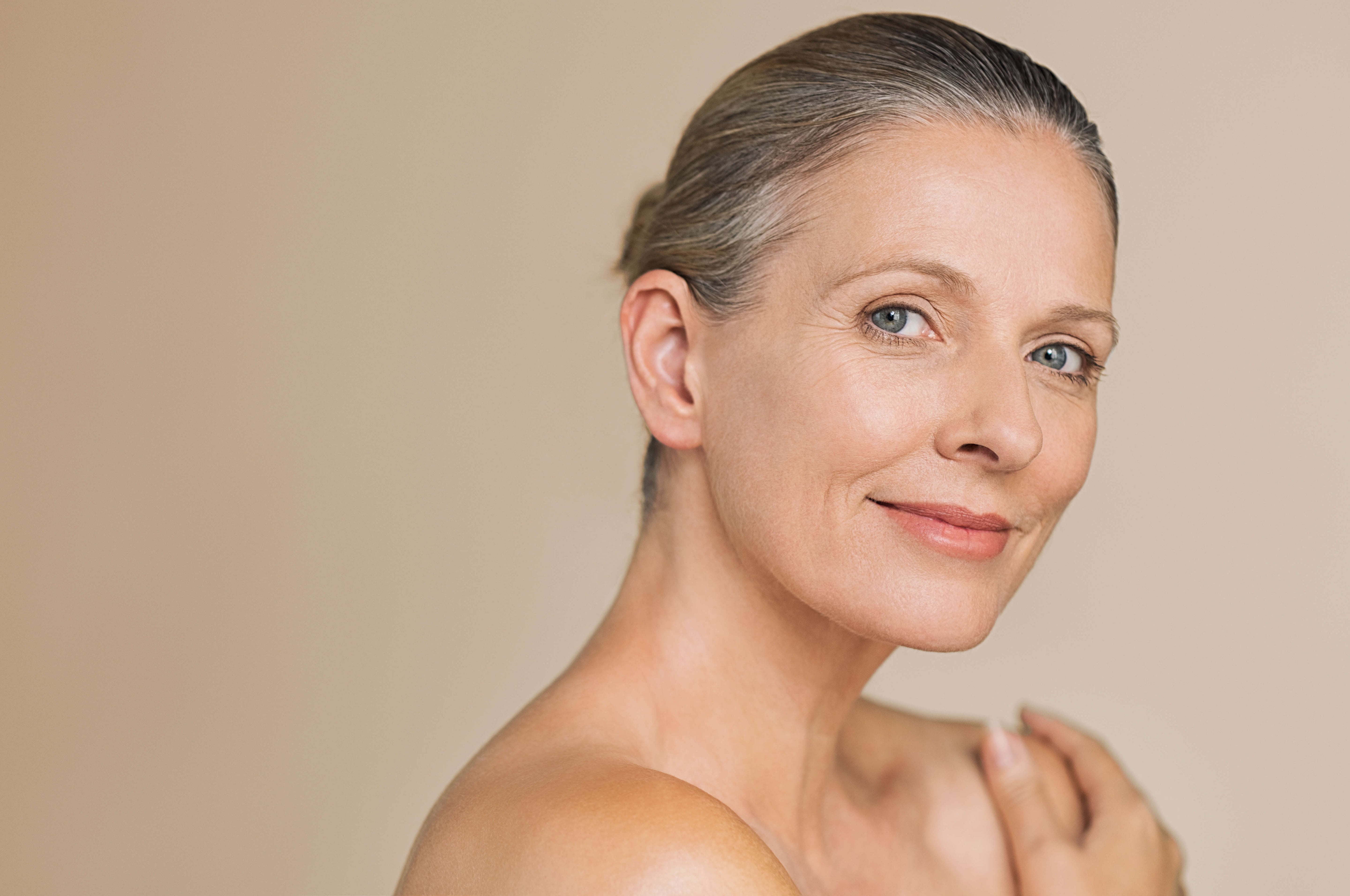 Woman with a neutral expression on a beige background