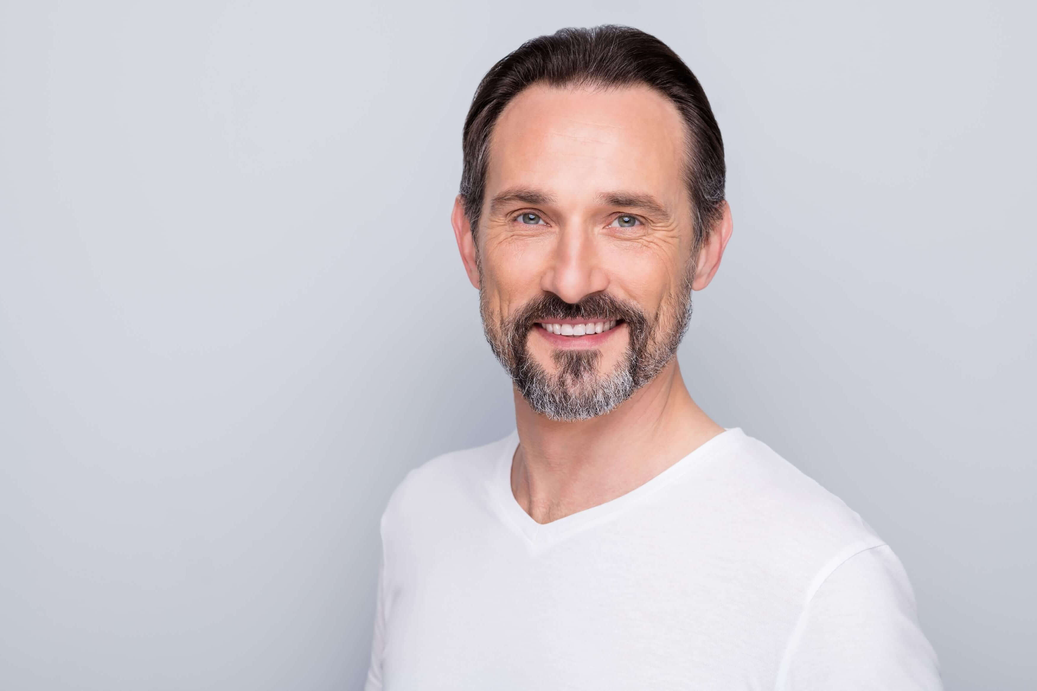 Man with a beard wearing a white shirt against a light gray background