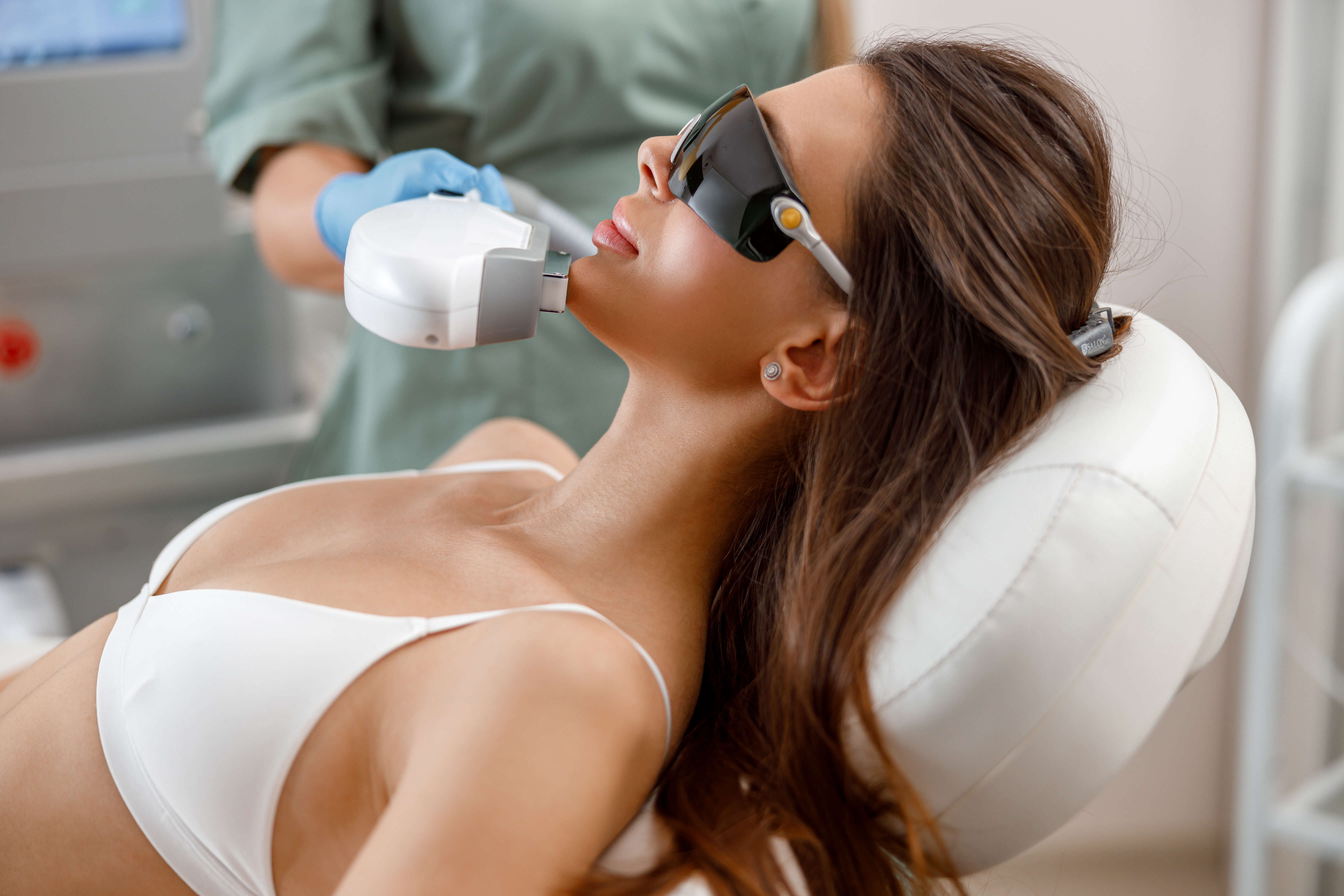 Woman receiving Intense Pulsed Light (IPL) treatment on face while wearing protective goggles